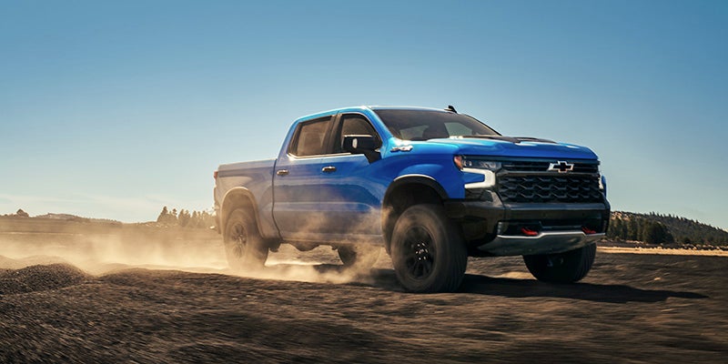 Blue Chevrolet Silverado 1500 kicking up dust in the desert