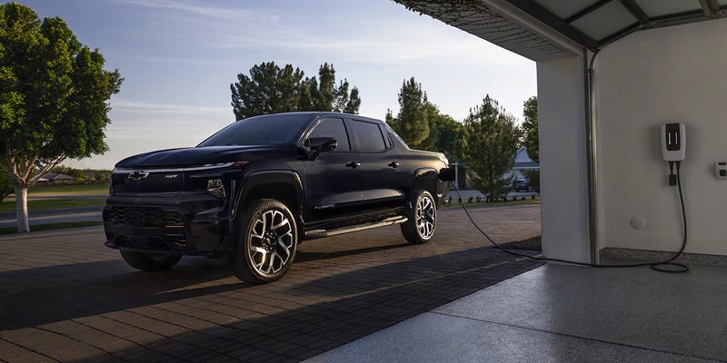 Chevrolet Silverado EV being charged at home next to a garage