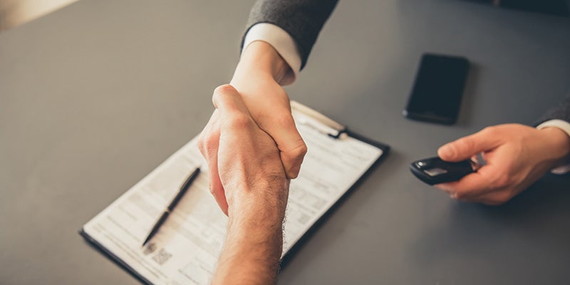 i.g. Burton Chevrolet of Berlin in Berlin MD close up of a customer shaking hands with a sales rep after signing finance paperwork