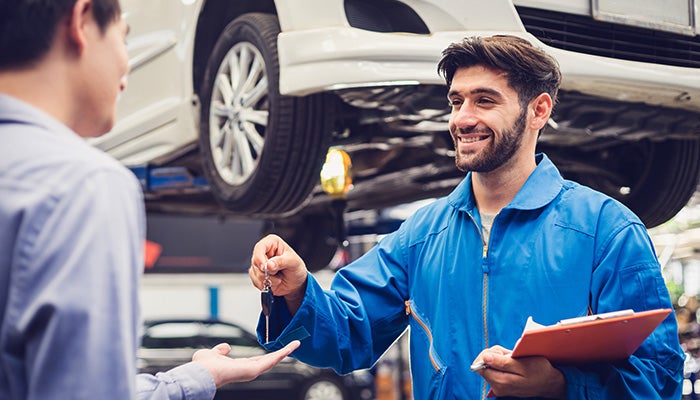 mechanic handing over keys to customer as they are done servicing the vehicle